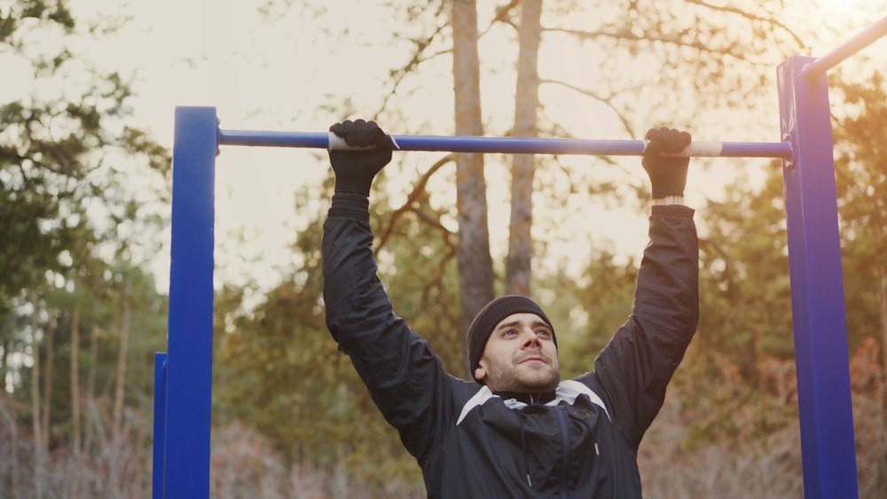 Man doing pull-ups on an outdoor bar in evening light